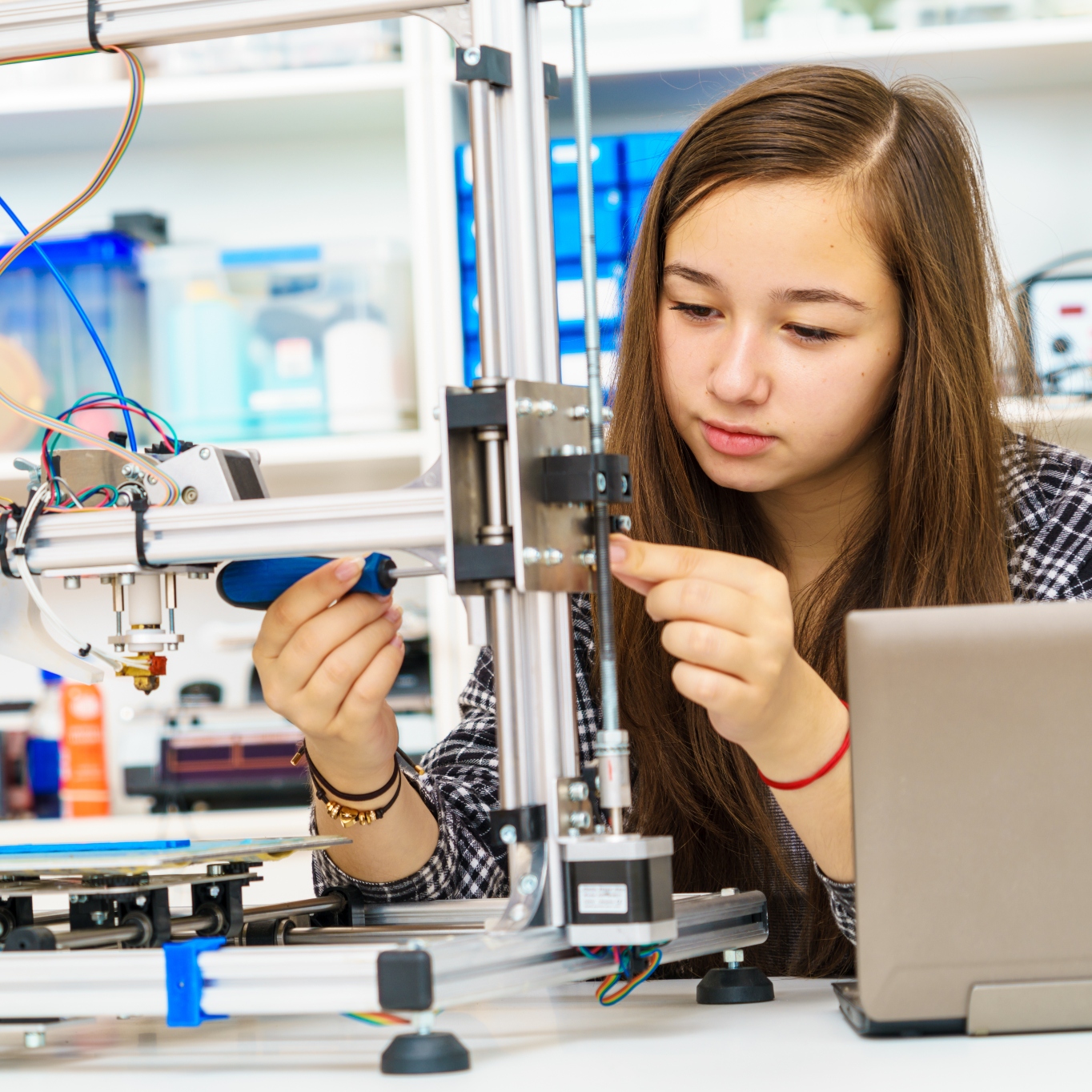 A young woman student fixes a robot